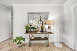A hallway with a wooden console table, a mirror, a lamp, a coat rack, and a potted plant. - Blu Sky Cottage | Waterfront Pool Home, Resort-Style Backyard, Near Siesta Key Village (Siesta Key)