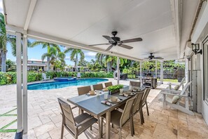 A covered patio with a pool, dining table, chairs, and ceiling fans. - Blu Sky Cottage | Waterfront Pool Home, Resort-Style Backyard, Near Siesta Key Village (Siesta Key)