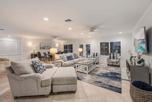 A spacious living room with a sofa set, a coffee table, and a dining area with chairs and a lamp. - Blu Sky Cottage | Waterfront Pool Home, Resort-Style Backyard, Near Siesta Key Village (Siesta Key)