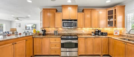 A kitchen with wooden cabinets, a stainless steel stove, a microwave, and a ceiling fan.