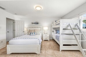 A bedroom with a bunk bed, a single bed, a nightstand, a lamp, and a wall-mounted fish decoration.