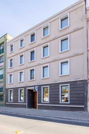 A multi-story building with a flat facade, rectangular windows, and a ground-level entrance. - Black Cat Hostal Boutique (Santiago)