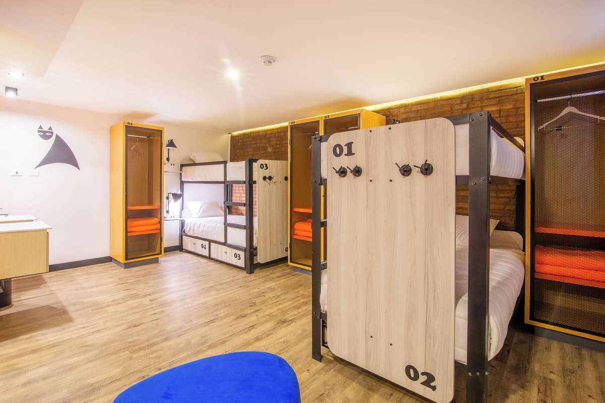 A hotel room with bunk beds, a desk, and a blue chair.