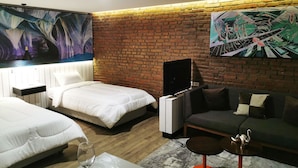 Une chambre d’hôtel moderne avec un mur en briques, deux lits, un canapé, une télévision et des œuvres d’art accrochées aux murs.