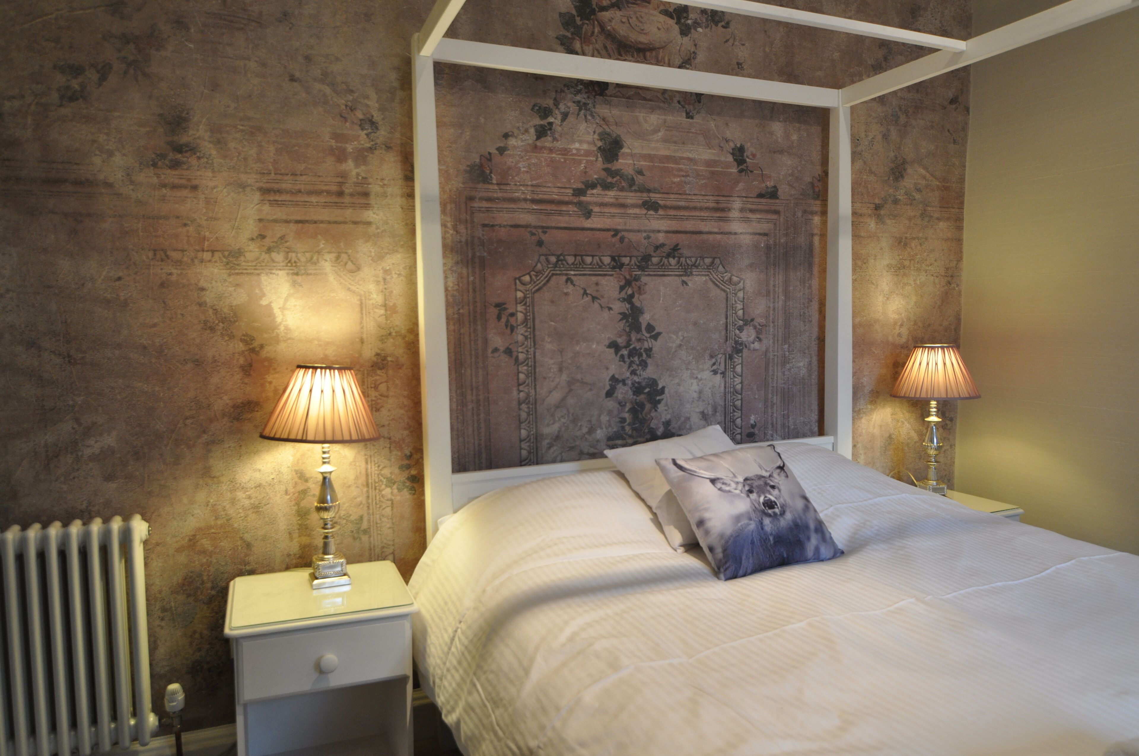 Une chambre à coucher avec un lit à baldaquin, deux lampes de chevet et un radiateur.