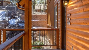 A wooden cabin with a balcony, a welcome sign, and a view of a snowy landscape.