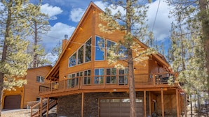A large wooden cabin with a balcony, large windows, and a garage.