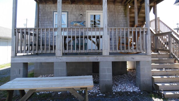 A wooden deck with a railing, a bench, and a door with a 'Welcome' sign. - Two separate Apartments (Wachapreague)