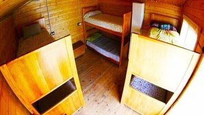 Eine Holzjagdhaushälfte mit Etagenbetten, einem kleinen Tisch und einem Fenster.