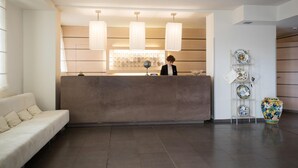 A hotel reception area with a modern design, featuring a reception desk, a sofa, and a decorative plate rack. - Da Vinci (Vinci)