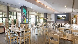 A spacious restaurant with multiple tables and chairs, large windows, and a mural on the wall. - Da Vinci (Vinci)