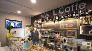 Una zona de bar con mostrador, taburetes y una variedad de botellas y vasos.
