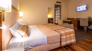 A hotel room with a bed, a desk, a chair, a television, and a bathroom visible through an open door. - Da Vinci (Vinci)
