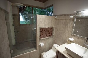A bathroom with a glass-enclosed shower, a toilet, and a sink.