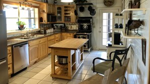 A kitchen with wooden cabinets, a central island, a stove, and a hanging pot rack.
