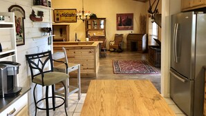 A kitchen with wooden cabinets, a refrigerator, a coffee machine, and a dining area with a table and chairs.
