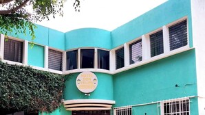 Um hotel chamado "Hotel Don Felipe Restaurante" com fachada curva, várias janelas e plantas em vasos na frente.