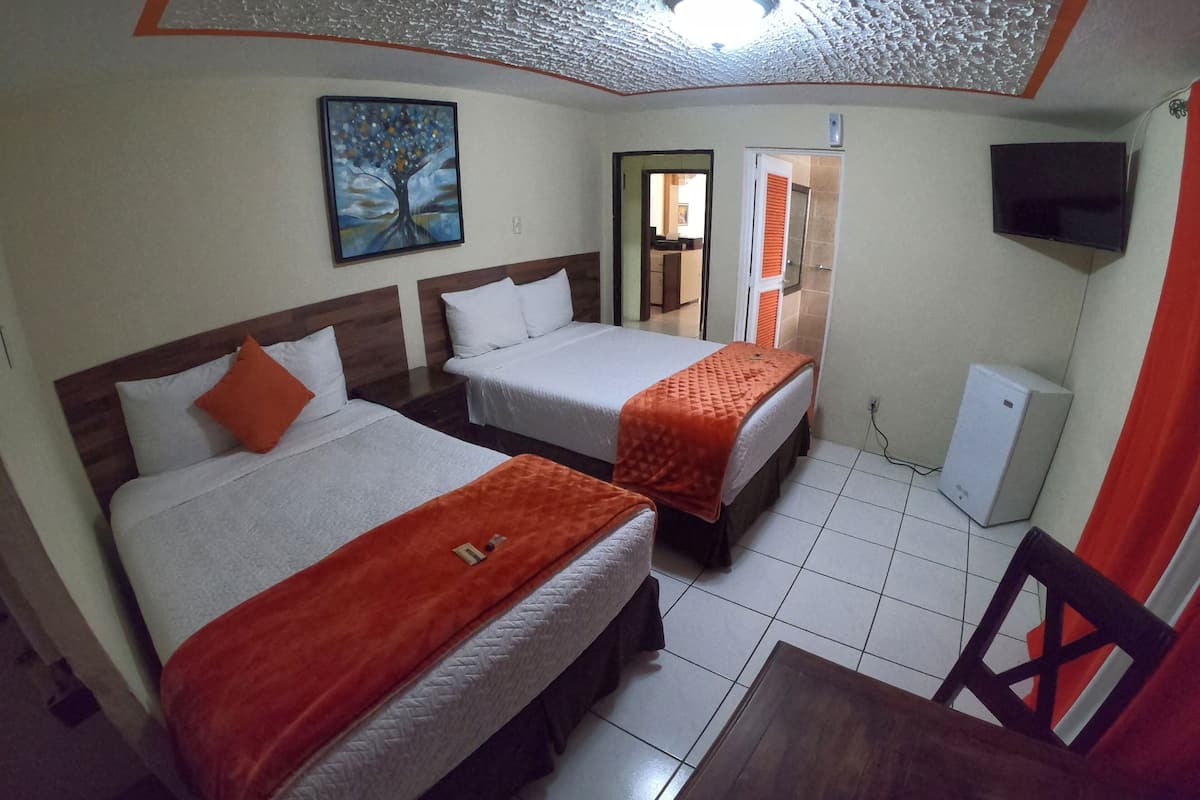 Quarto de hotel com duas camas, uma televisão e um quadro na parede.