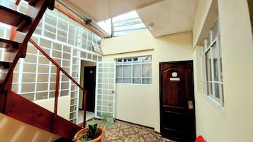 Una escalera con barandilla de madera que lleva a una plataforma con una planta en maceta.
