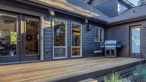 A modern house with large windows, a deck, and a barbecue grill.