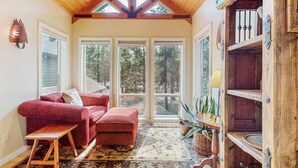 A cozy room with a red sofa, a wooden bench, a patterned rug, and a wooden cabinet with shelves.