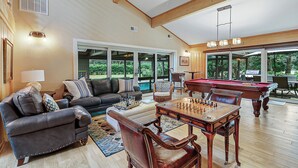 A spacious living room with a pool table, leather sofas, and a billiards table.