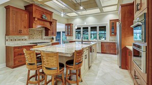 A spacious kitchen with a large island, wooden cabinets, and a view to the outdoors.