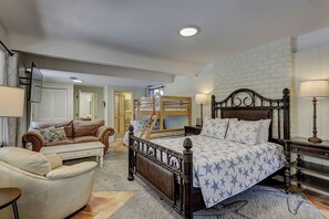 Een slaapkamer met een stapelbed, een slaapbank, een nachtkastje en een lamp.
