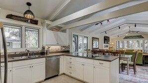 Uma cozinha espaçosa com armários brancos, uma ilha central e uma área de jantar com mesa e cadeiras.