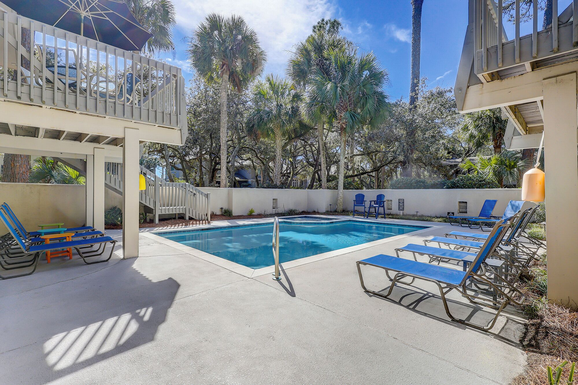 A pool area with lounge chairs and a wooden deck.