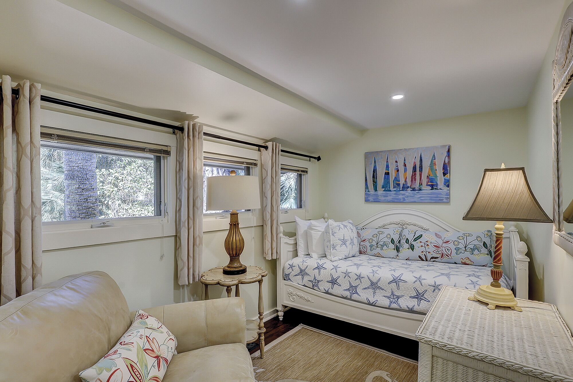 A bedroom with a bed, a nightstand, a lamp, a painting, and a window with curtains.
