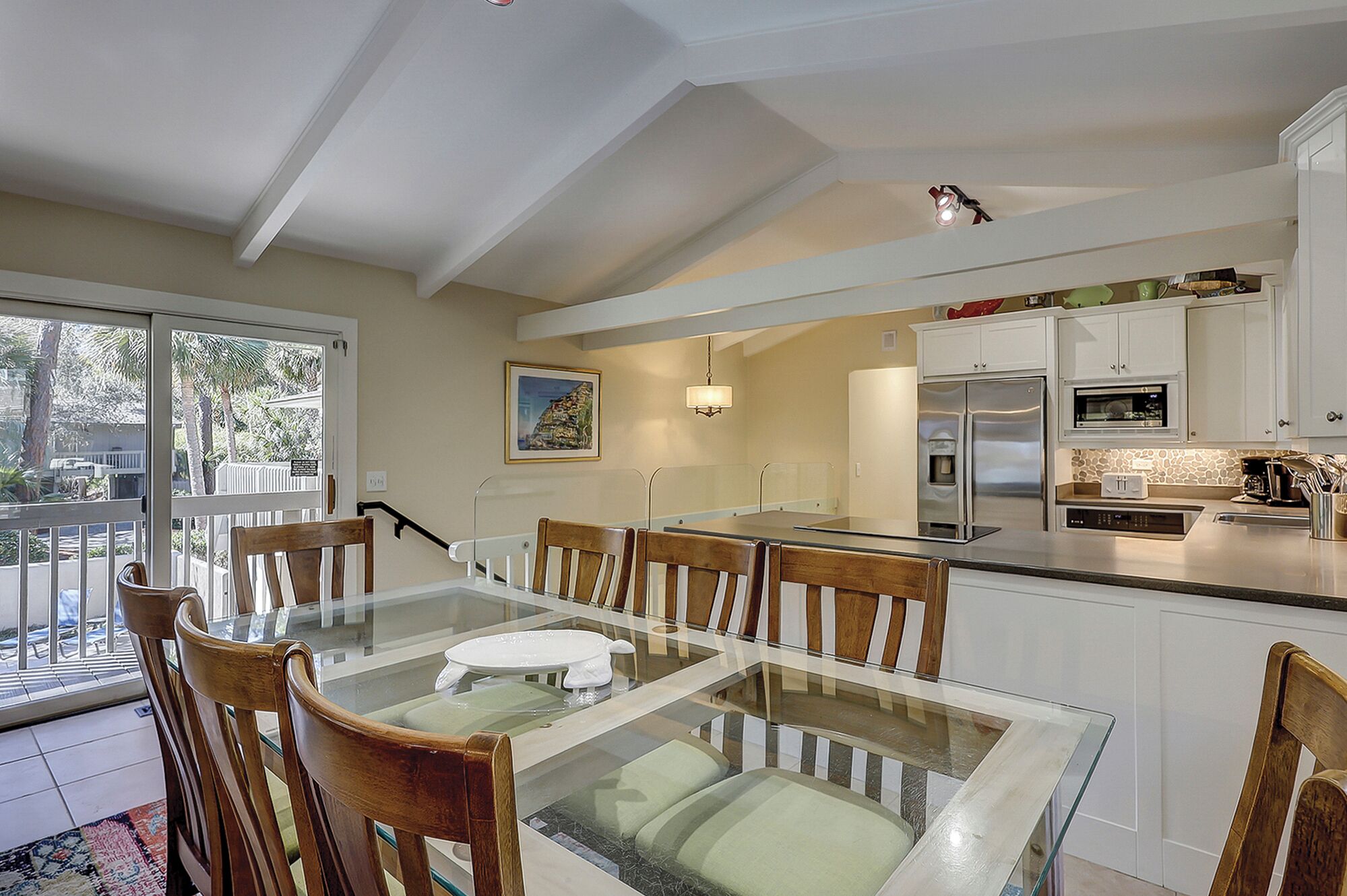 A modern kitchen with white cabinets, stainless steel appliances, and a glass dining table.