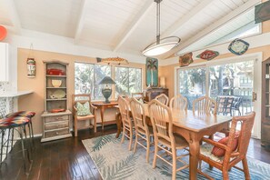A dining area with a wooden table and chairs, a chandelier, and a view of the outdoors. - Classic DOG FRIENDLY Five Bedroom 2nd Row Ocean Sea Pines Home with a Pool (Hilton Head Island)