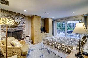A bedroom with a fireplace, a bed, a sofa, and a view of the outdoors. - Classic DOG FRIENDLY Five Bedroom 2nd Row Ocean Sea Pines Home with a Pool (Hilton Head Island)