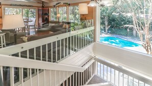Un espace de vie à plusieurs niveaux doté d’une balustrade en verre donnant sur une piscine.
