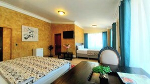 Una habitación de hotel con cama, escritorio, silla, televisor y ventana con cortinas.