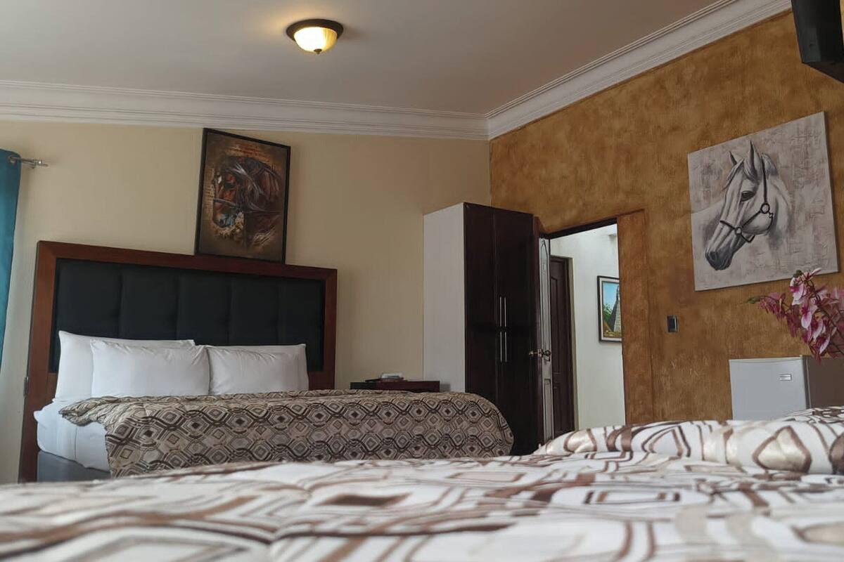 A hotel room with a large bed, a wardrobe, and a painting on the wall.