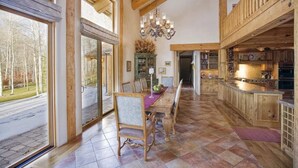 Una cocina amplia con armarios de madera, un comedor con mesa y sillas, y ventanas grandes que ofrecen vistas al exterior.