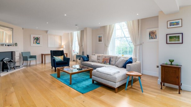 A spacious living room with a sofa, armchairs, a coffee table, and a fireplace. - GuestReady - Spacious Apartment in Clapham Town (London)