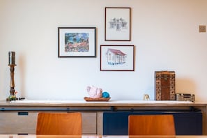 A dining area with a wooden table, chairs, and a decorative bowl on the wall.