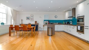 A modern kitchen with wooden flooring, white cabinets, and stainless steel appliances. - GuestReady - Spacious Apartment in Clapham Town (London)