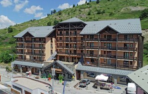 A multi-story hotel with balconies, a ski lift, and a sign for 'InterSport'. - Duplex 8 beds, 50m from the slopes, Coeur Station (Valmeinier)
