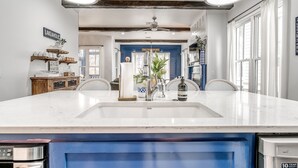 A kitchen with a large island, two pendant lights, a ceiling fan, and a view into the dining area. - Carlton Landing! Gorgeous Home on Redbud Park (Carlton Landing)