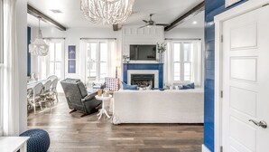 A spacious living room with a fireplace, a dining area with a white table and chairs, and a large chandelier. - Carlton Landing! Gorgeous Home on Redbud Park (Carlton Landing)