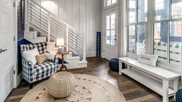 A spacious living area with a staircase, a chandelier, a bench, and a large window. - Carlton Landing! Gorgeous Home on Redbud Park (Carlton Landing)