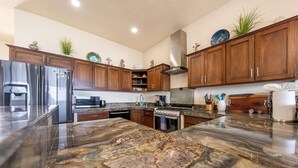 A modern kitchen with wooden cabinets, a granite countertop, stainless steel appliances, and decorative items.