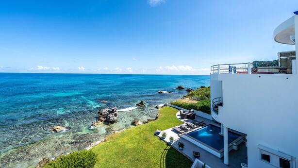 A modern hotel with a pool, ocean view, and a balcony overlooking the sea.