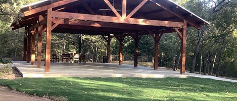 Situated in a serene park-like setting, this pavilion offers a tranquil escape surrounded by trees and a well-maintained lawn.