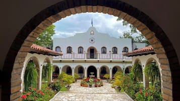 A courtyard with a white building, arched walkways, and potted plants.