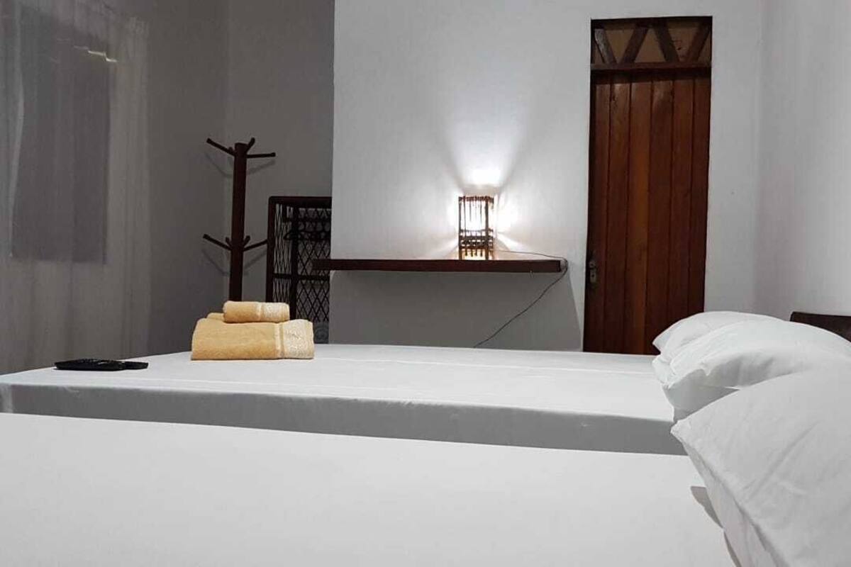 Een strak ingerichte hotelkamer met een bed, een nachtkastje, een lamp en een houten deur.